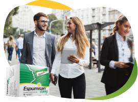 Dvije mlade žene i mladić u poslovnoj odjeći energično šetaju gradom, u prvom planu je pakiranje Espumisan Easy granula